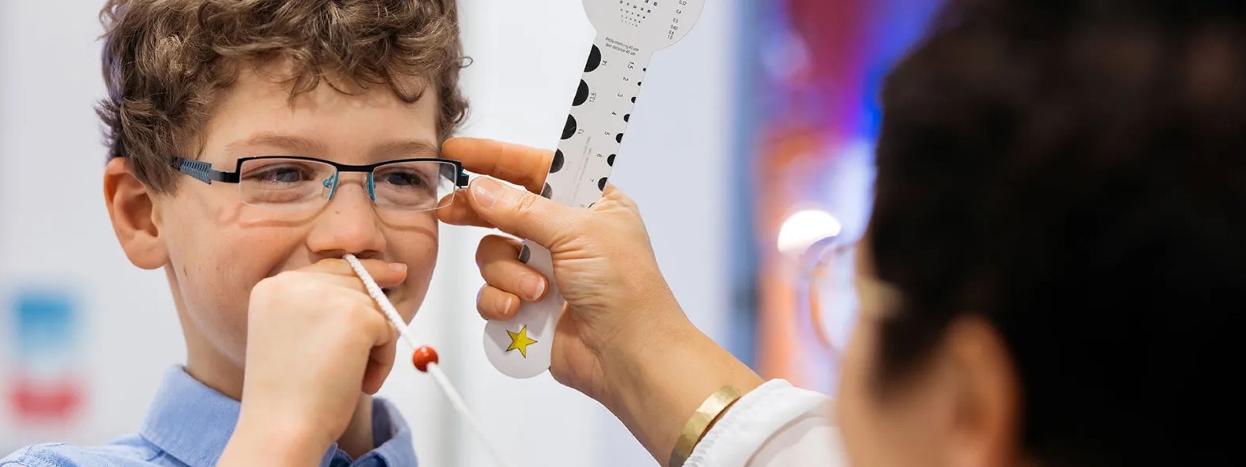 Kind während einer optometrischen Messung / Visualtraining mit der Prockschnur